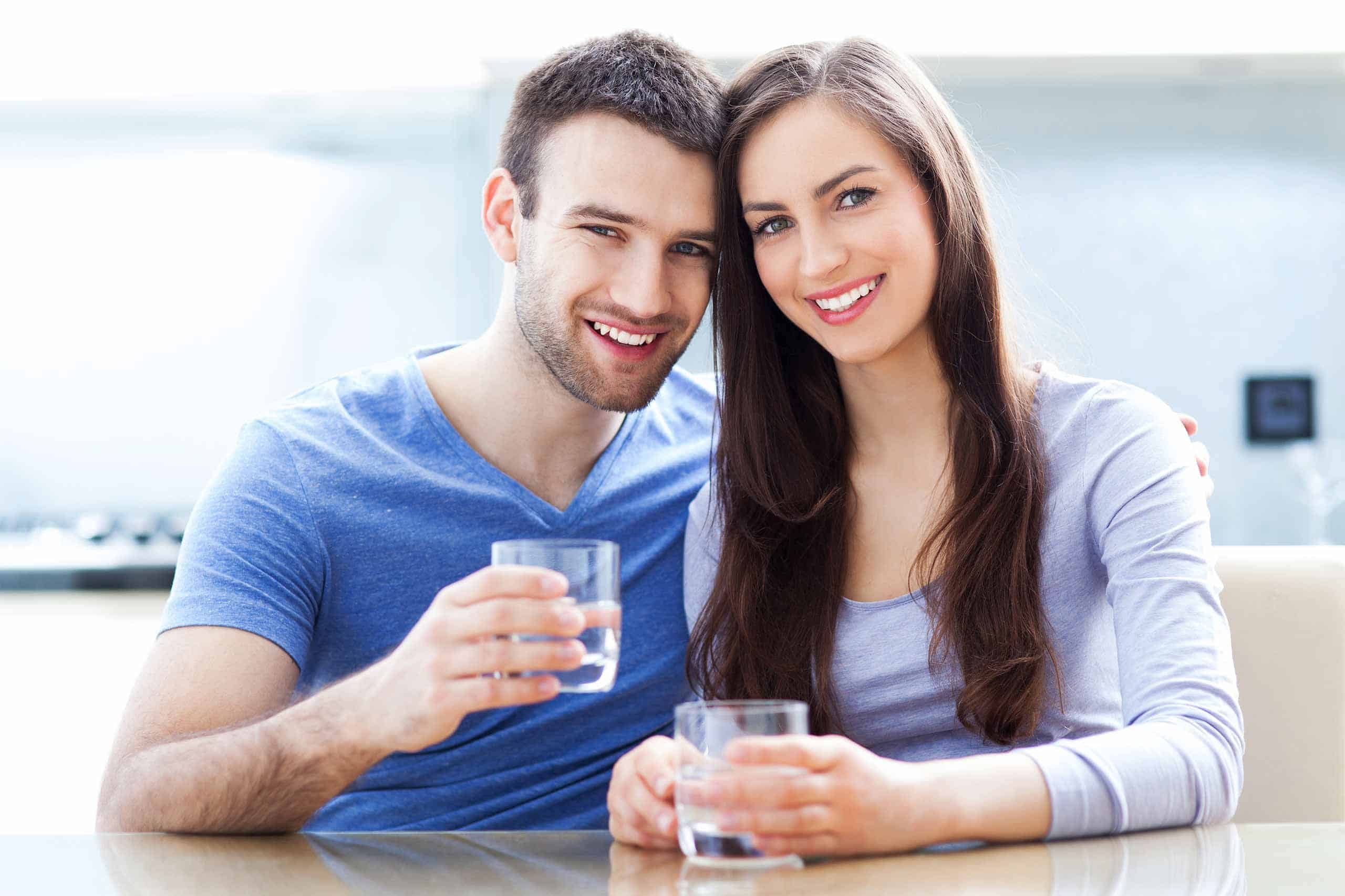 Couple drinking clean pure water together in kitchen